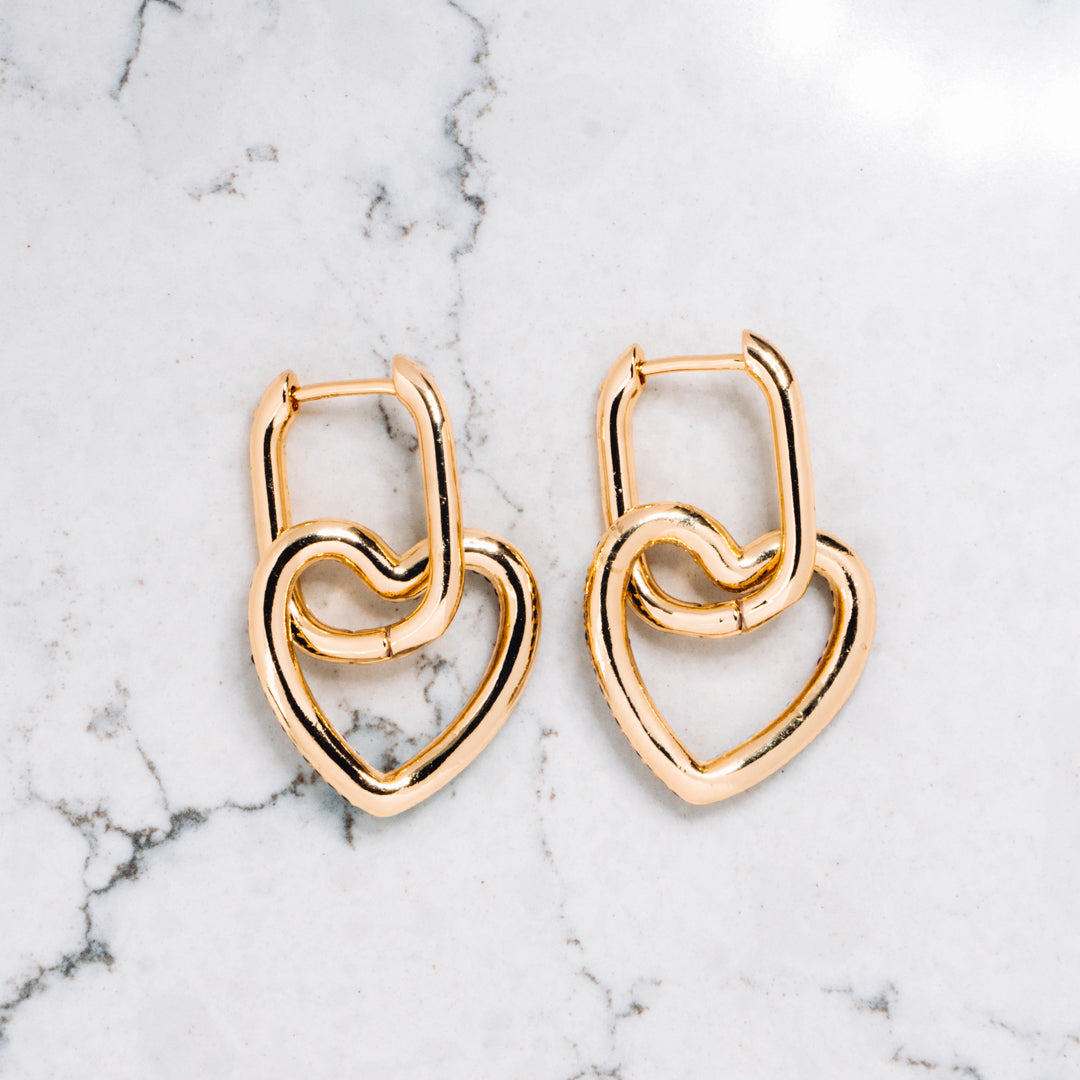 Gold tone earrings with heart shaped pendants in gold tone.