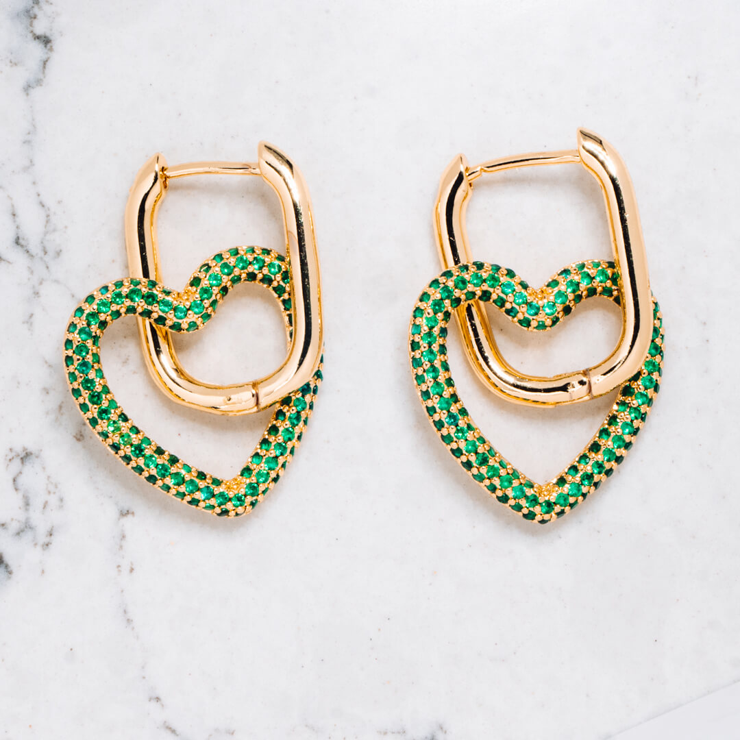 Gold tone earrings with heart shaped pendants in gold tone with emerald green coloured zircon stones.