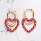 Gold tone earrings with heart shaped pendants in gold tone with pink coloured zircon stones.